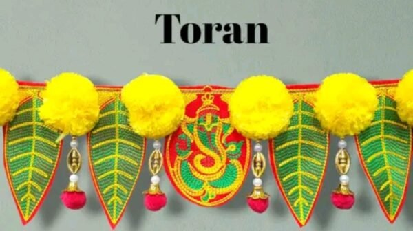 Close-up of Lord Ganesh embellishment on the handcrafted mango pan toran, surrounded by green embroidered leaves and yellow artificial flowers.